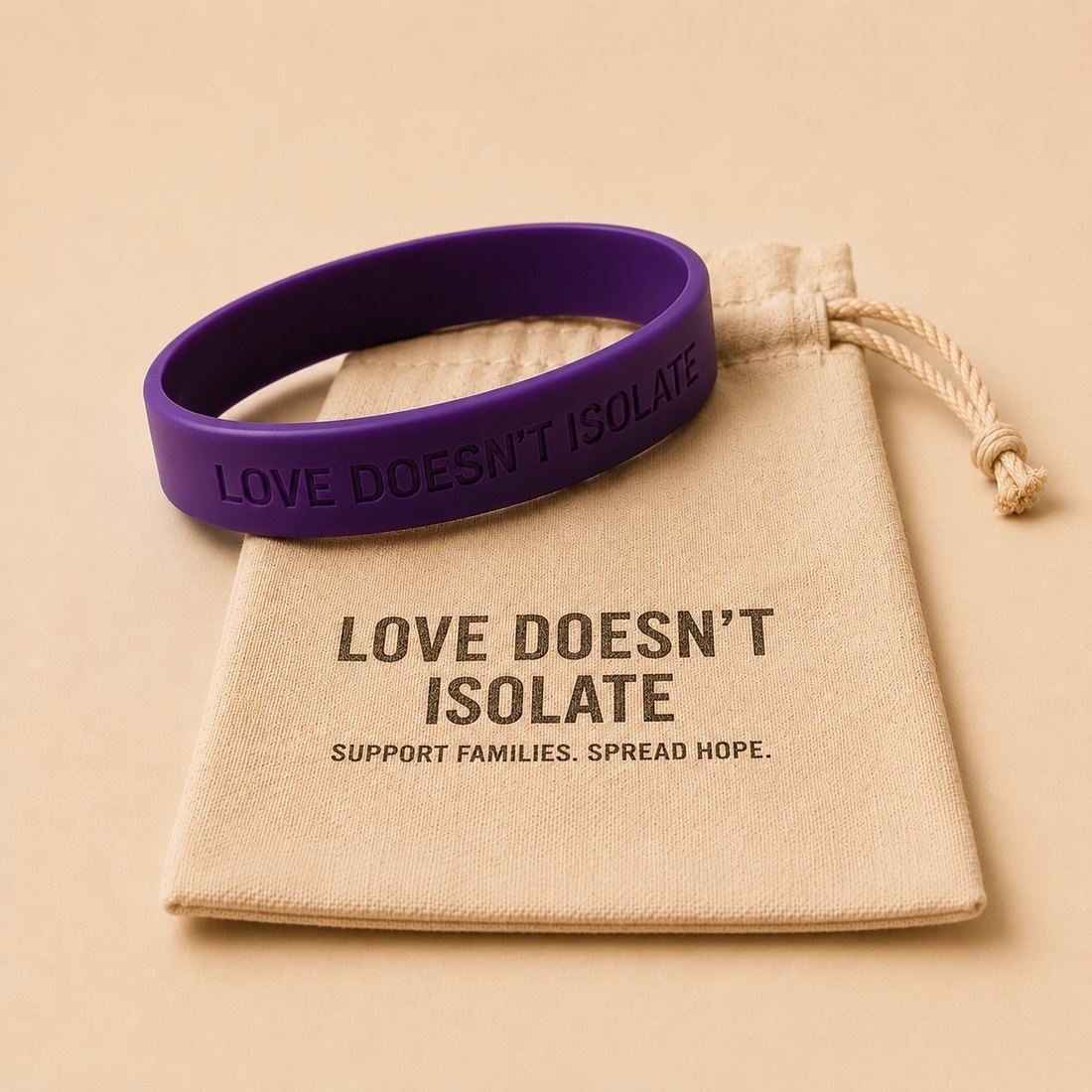 Purple Love Doesn't Isolate silicone wristband resting on a branded drawstring pouch